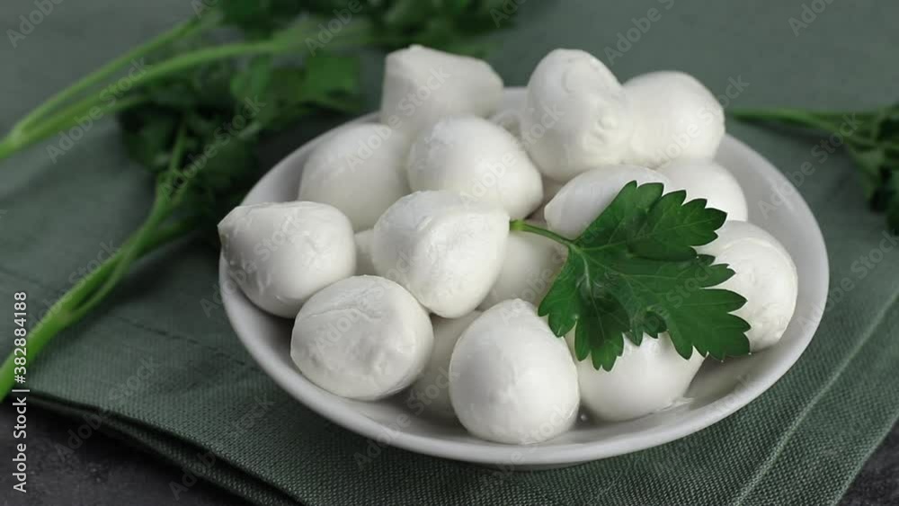 round pieces of mozzarella cheese and green parsley on a white plate close-up, pan movement of the camera round pieces of mozzarella cheese and green parsley on a white plate close-up, pan movement of the camera