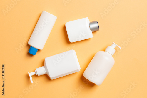 Set of White Cosmetic containers isolated on colored background, top view with copy space. Group of plastic bodycare bottle containers with empty space for you design