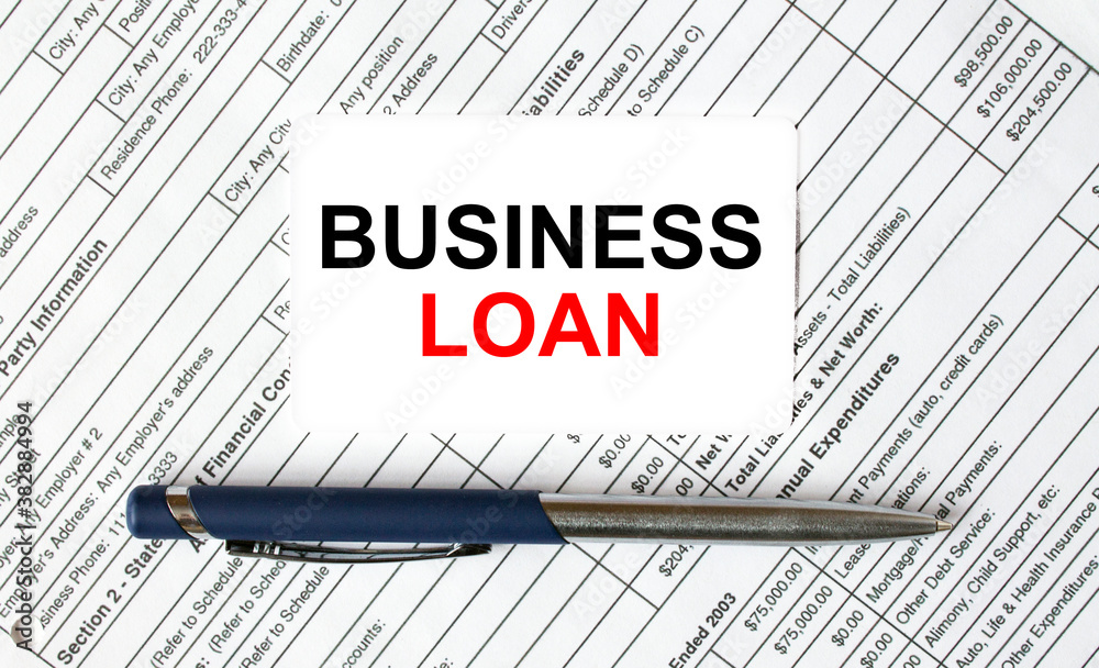 Text Business Loan written on a business card lying on financial tables with a blue metal pen Text Business Loan written on a business card lying on financial tables with a blue metal pen
