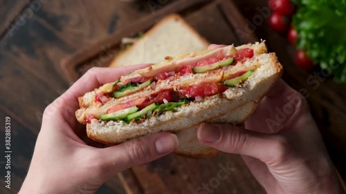Eating club sandwich. Female hand holding big juicy club sandwich
