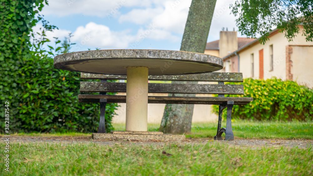 Ground view of a round stone table and bench, outdoors	