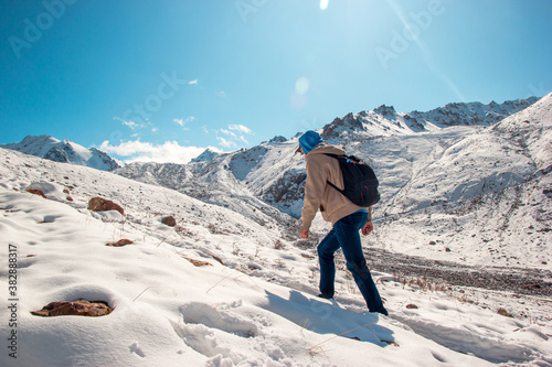 A man rises on a snow slope to a mountain peak in winter.