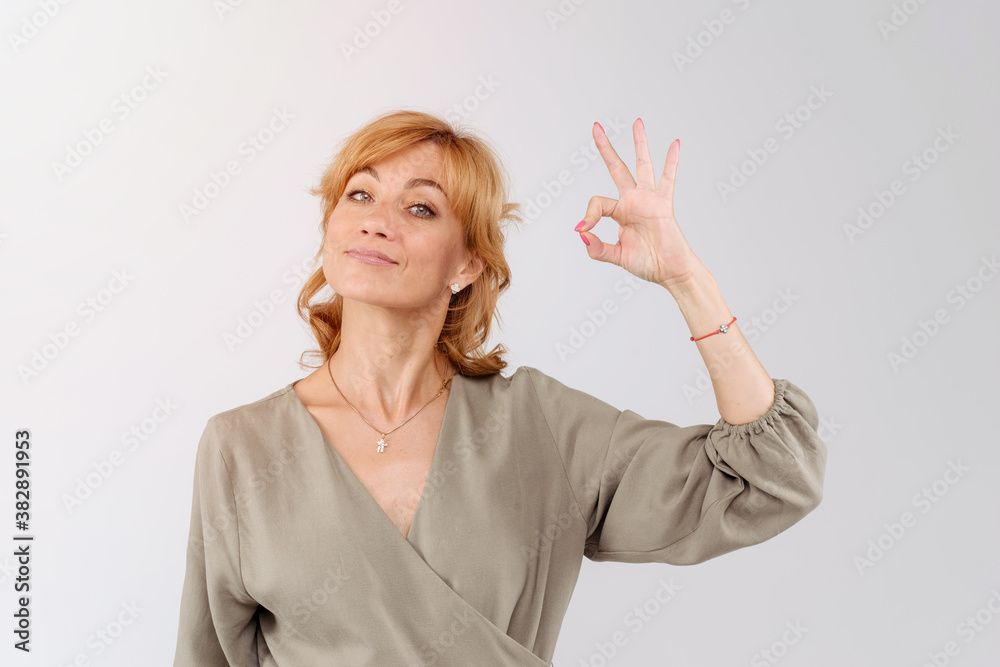 Obraz premium Happy mature woman showing ok symbol. Joyful smiling woman gesturing okey sign and looking at camera. Isolated on white. Positivity concept