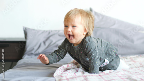 Portrait of very sweet little child. 1 year old baby crawling on the bed