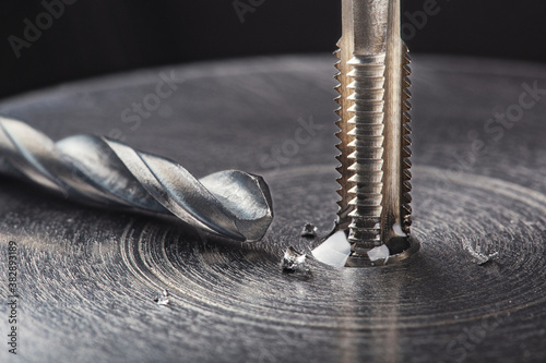 Foto Thread tap drill steel billet with drill bit on background