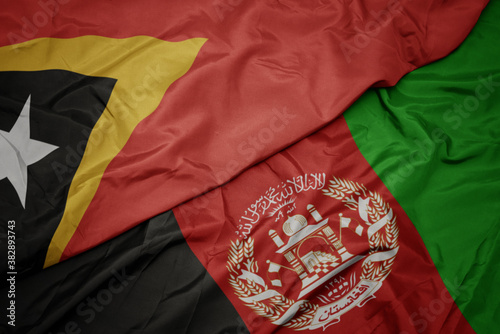 waving colorful flag of afghanistan and national flag of east timor. macro