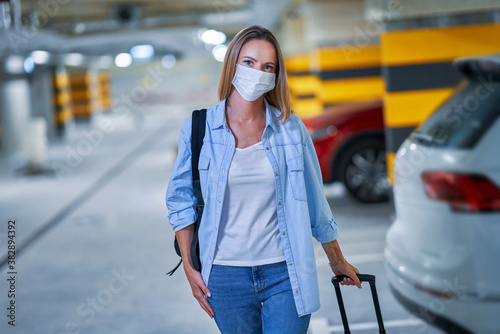Adult woman tourist wearing mask in underground airport parking lot