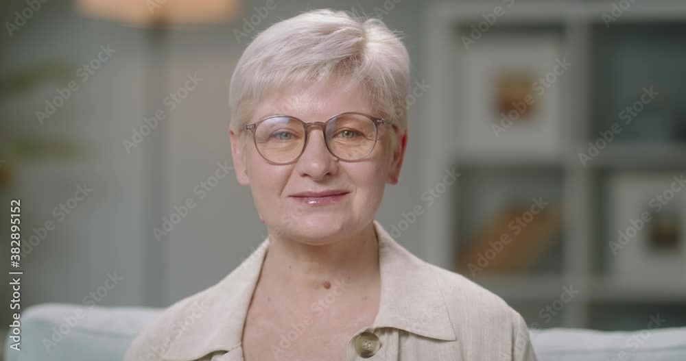 Joyful senior caucasian woman at home looking at camera and positively smiling, mature model posing for video 4k portrait shot Joyful senior caucasian woman at home looking at camera and positively smiling, mature model posing for video 4k portrait shot
