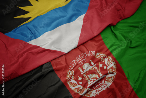 waving colorful flag of afghanistan and national flag of antigua and barbuda. macro