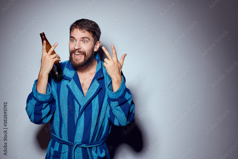 man with alcoholic drink in a bottle and in a blue robe on a light background cropped view