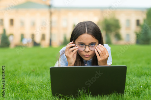 anti-reflective coating glasses. online education. back to school. teen girl use computer in park. child in glasses with notebook. new technology in modern life. serious kid work on laptop photo