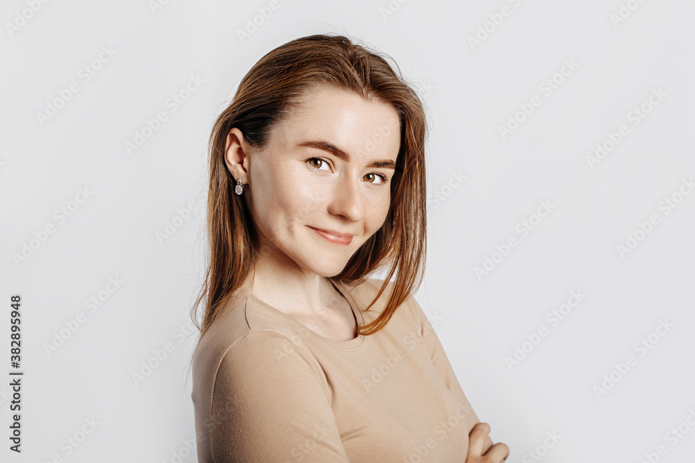 Beautiful young girl smiling and posing looking at the camera on a white isolated background. Positive brunette woman in a beige jumper. Kind look. Beautiful young girl smiling and posing looking at the camera on a white isolated background. Positive brunette woman in a beige jumper. Kind look.