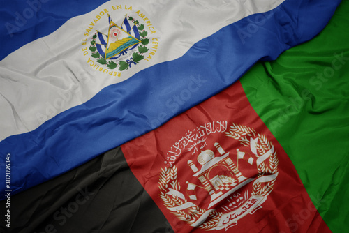 waving colorful flag of afghanistan and national flag of el salvador. macro