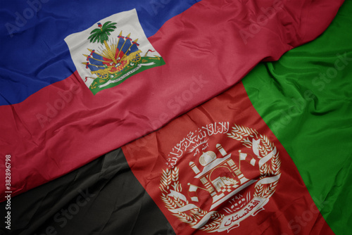 waving colorful flag of afghanistan and national flag of haiti. macro