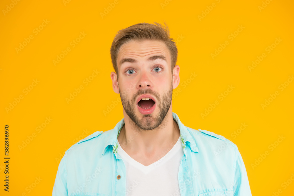 what a surprise. male summer casual fashion style. surprised guy has groomed hair on yellow background. human emotions. sexy boy with trendy hairstyle wear shirt. handsome unshaven man with bristle