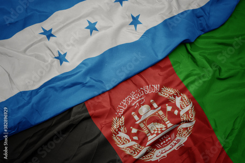 waving colorful flag of afghanistan and national flag of honduras. macro