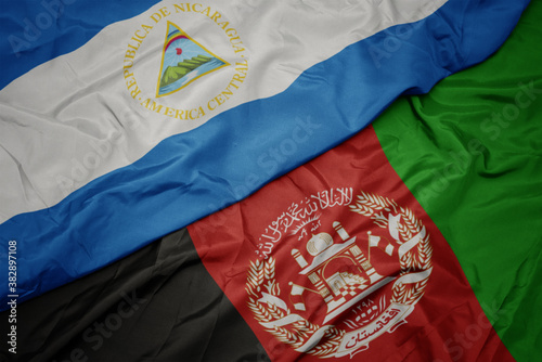 waving colorful flag of afghanistan and national flag of nicaragua. macro