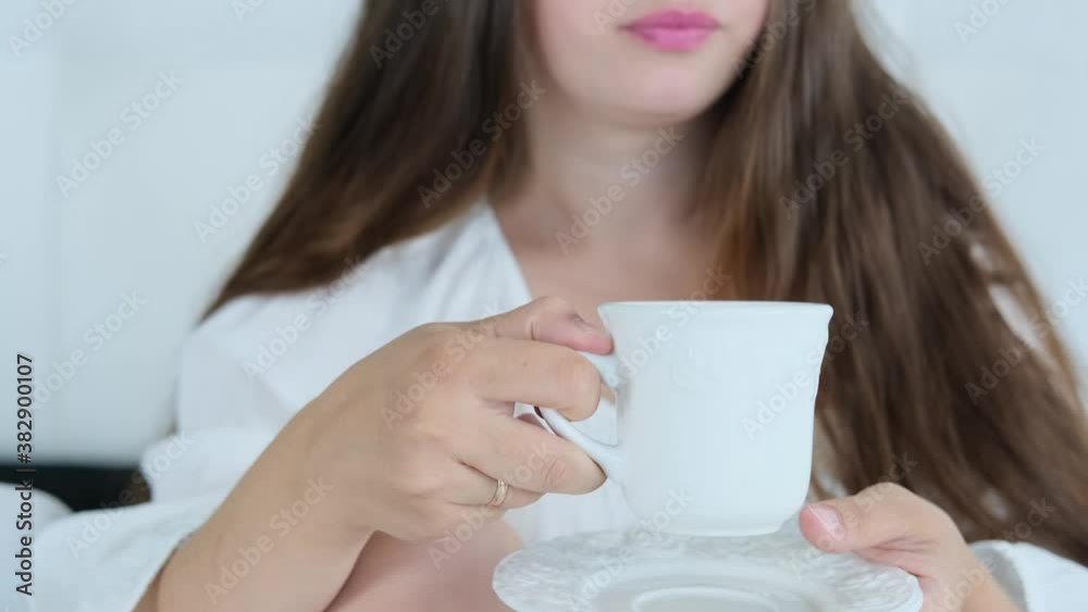 young woman in white clothes drinking tonic coffee, tea from a cup in bed, lush long hair, beauty and health concept, lifestyle, cozy home young woman in white clothes drinking tonic coffee, tea from a cup in bed, lush long hair, beauty and health concept, lifestyle, cozy home