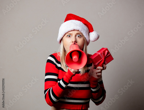 Style girl in Christmas hat with megaphone and gift box