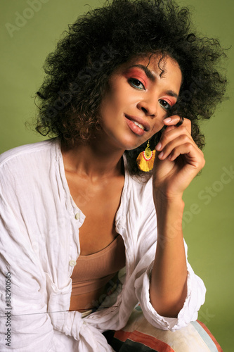 Close up portrait of African woman with bright colourful; make up posing over green background.