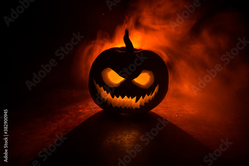 Halloween pumpkin smile and scary eyes for party night. Close up view of scary Halloween pumpkin with eyes glowing inside at black background photo