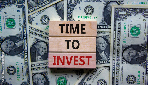 Concept text 'time to invest' on wooden blocks on a beautiful background from dollar bills. Business concept.