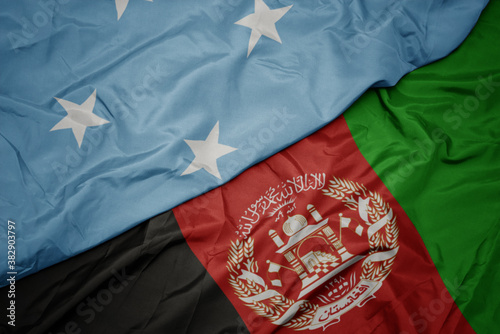 waving colorful flag of afghanistan and national flag of Federated States of Micronesia . macro