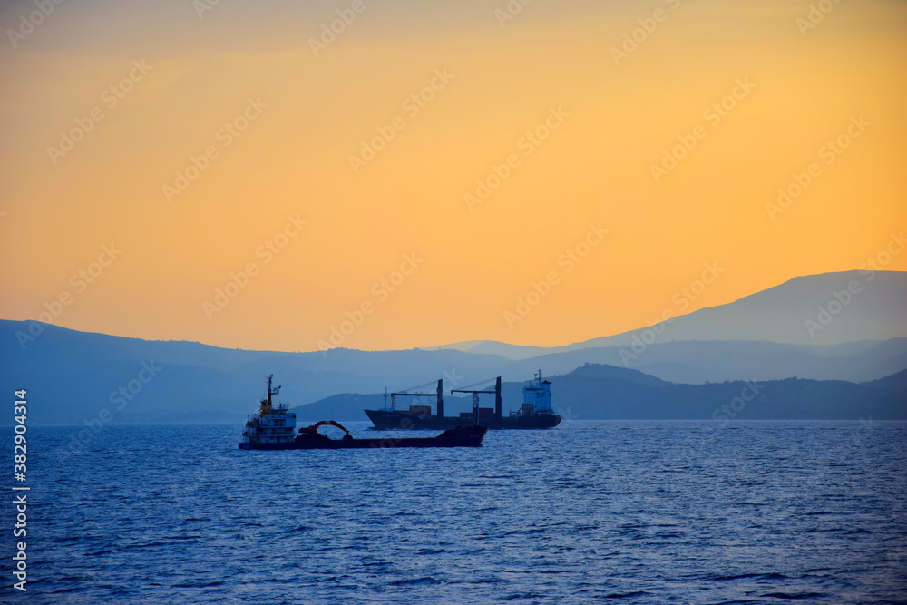 Obraz premium cargo ship travels at sunset