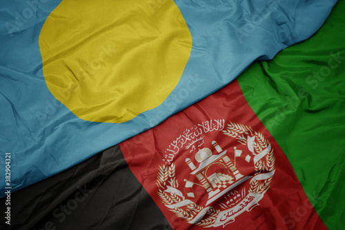 waving colorful flag of afghanistan and national flag of Palau . macro