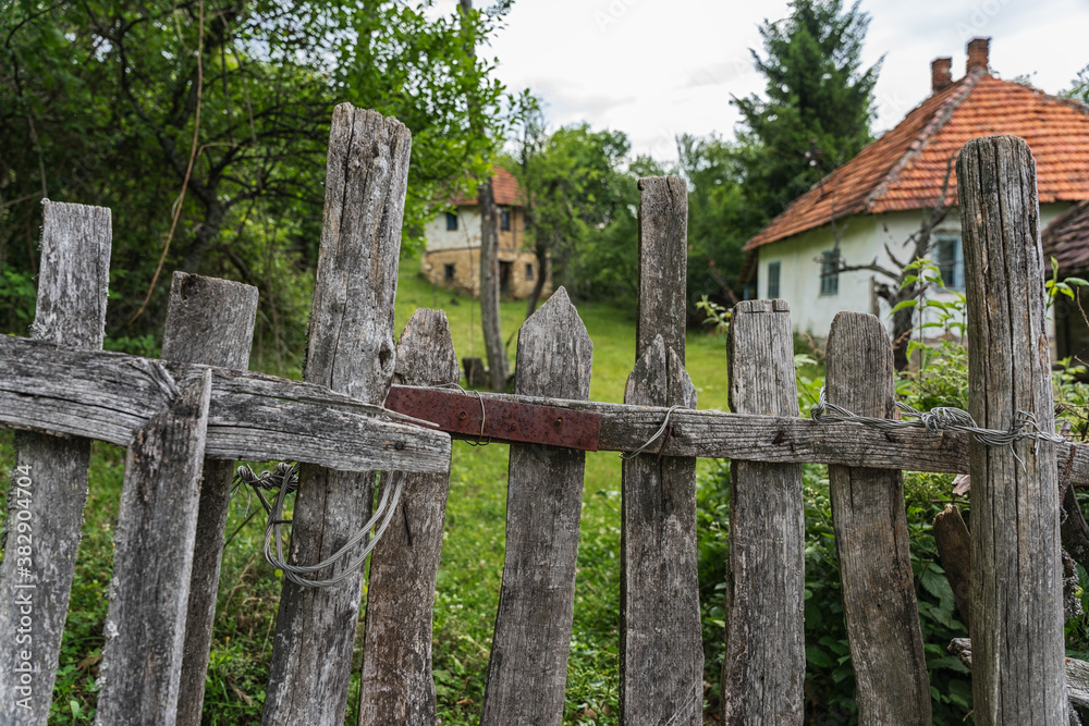 Old rundown wooden fence and abandoned houses in the background Old rundown wooden fence and abandoned houses in the background