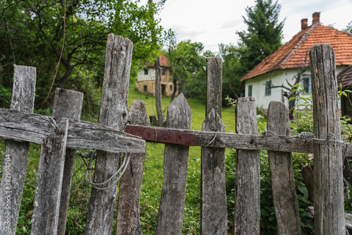 Old rundown wooden fence and abandoned houses in the background