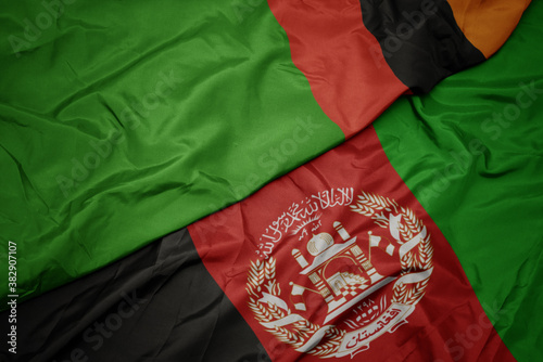 waving colorful flag of afghanistan and national flag of zambia. macro