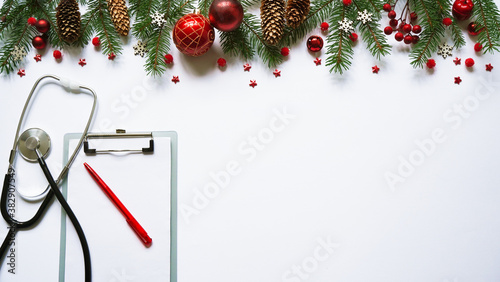 Christmas medical banner fir branches, cones, red balls, snowflakes, stethoscope and tablet on white background top view. Copyspace. Medicine new year flatly