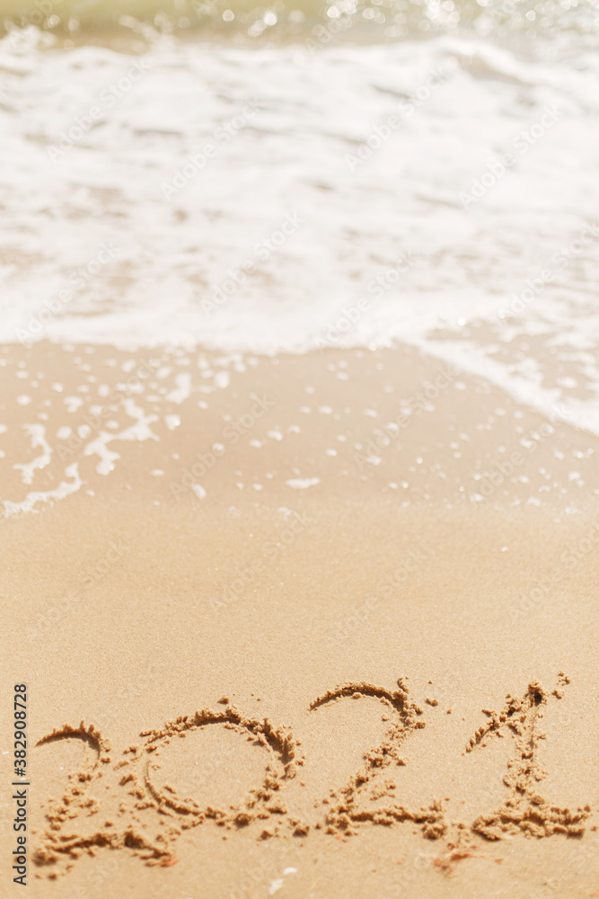Hello 2021! Happy new year 2021 sign handwritten on sandy beach with waves and white foam Hello 2021! Happy new year 2021 sign handwritten on sandy beach with waves and white foam