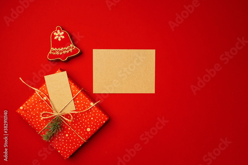 Blank sheet of paper with Christmas gift and gingerbread cookies on red background