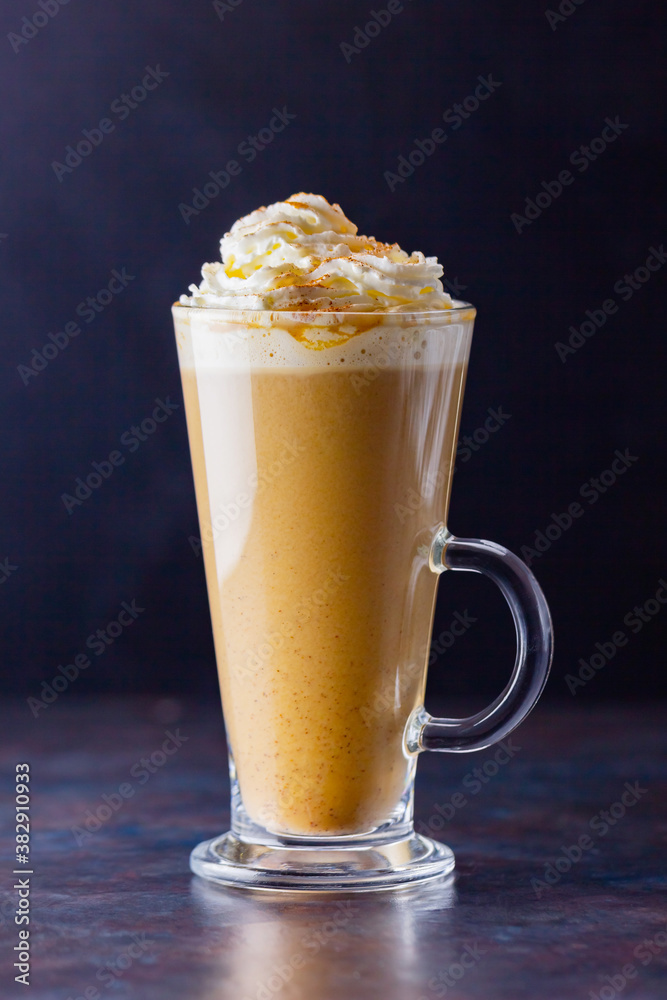 Pumpkin latte on a dark background. Pumpkin spice latte with whipped cream. Autumn drink. Minimalism. Copy space Pumpkin latte on a dark background. Pumpkin spice latte with whipped cream. Autumn drink. Minimalism. Copy space