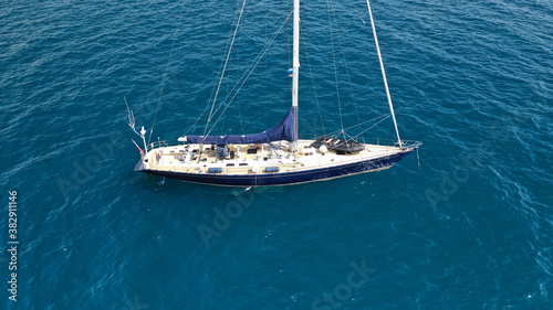 Aerial drone photo of beautiful sailboat anchored in Aegean deep blue sea