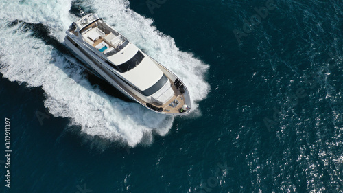 Aerial drone photo of small luxury yacht with wooden deck cruising open ocean deep blue sea