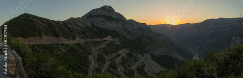 Panorama of epic roads in the north albanian mountains, famous curves and hairpin turns of SH20 road above the Cem river gorge in morning. Sun is just rising over the mountains.
