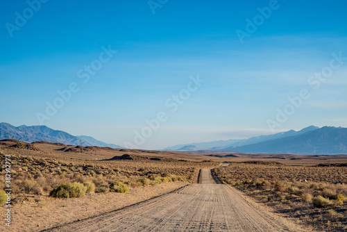 dirt road in desert valley heading toward distant mountains in California 