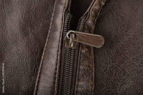 Close-up shot of a zip fastener on a brown belt.