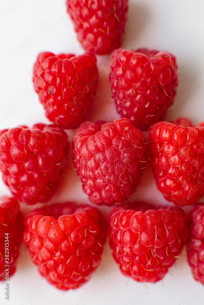 A picture of a few fresh pink raspberries lies on a white background. Background and picture for postcard. A picture of a few fresh pink raspberries lies on a white background. Background and picture for postcard.