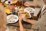 Hands of mature husband and wife praying by festive table served for dinner