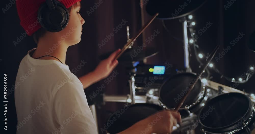 Cool and talented young boy playing drums in white tshirt performing song in dark background feeling super star on stage. Teenager rock band drummer