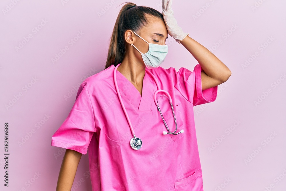 Young hispanic woman wearing doctor uniform and medical mask surprised with hand on head for mistake, remember error. forgot, bad memory concept. Young hispanic woman wearing doctor uniform and medical mask surprised with hand on head for mistake, remember error. forgot, bad memory concept.
