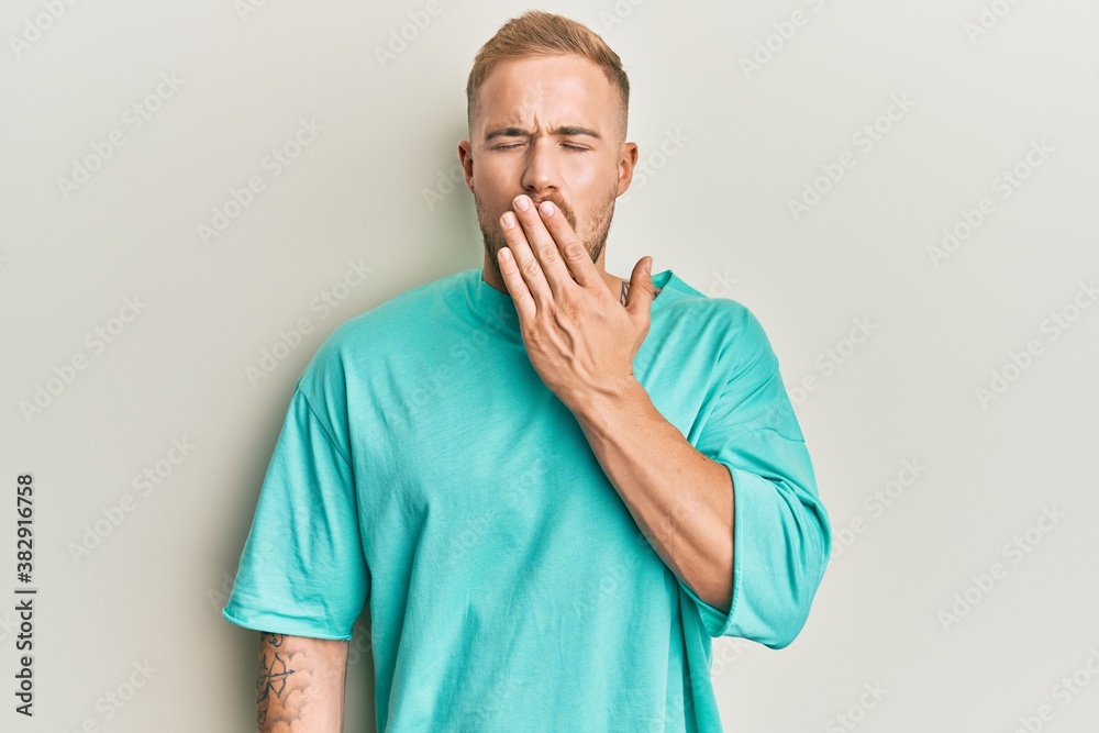 Young caucasian man wearing casual clothes bored yawning tired covering mouth with hand. restless and sleepiness. Young caucasian man wearing casual clothes bored yawning tired covering mouth with hand. restless and sleepiness.
