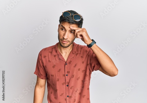 Young handsome man wearing casual summer clothes pointing unhappy to pimple on forehead, ugly infection of blackhead. acne and skin problem