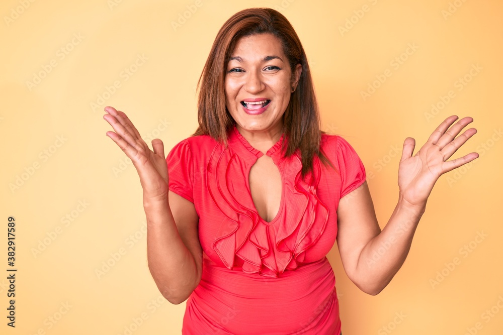 Middle age brunette hispanic woman wearing summer dress celebrating victory with happy smile and winner expression with raised hands Middle age brunette hispanic woman wearing summer dress celebrating victory with happy smile and winner expression with raised hands