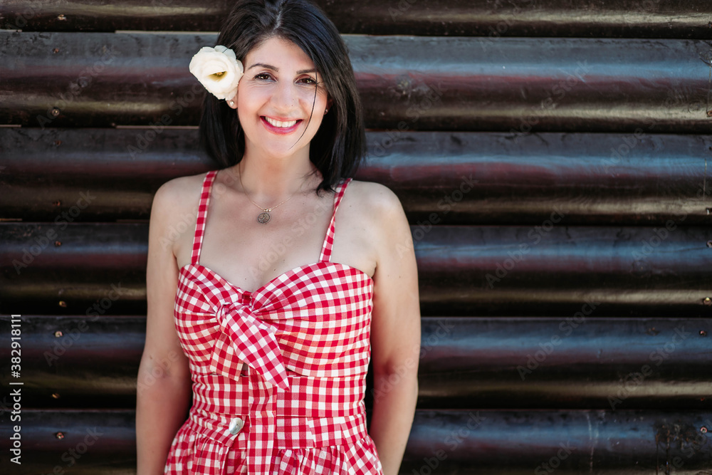 Brunette middle aged woman in red checkered dress and white flower in her hair Brunette middle aged woman in red checkered dress and white flower in her hair