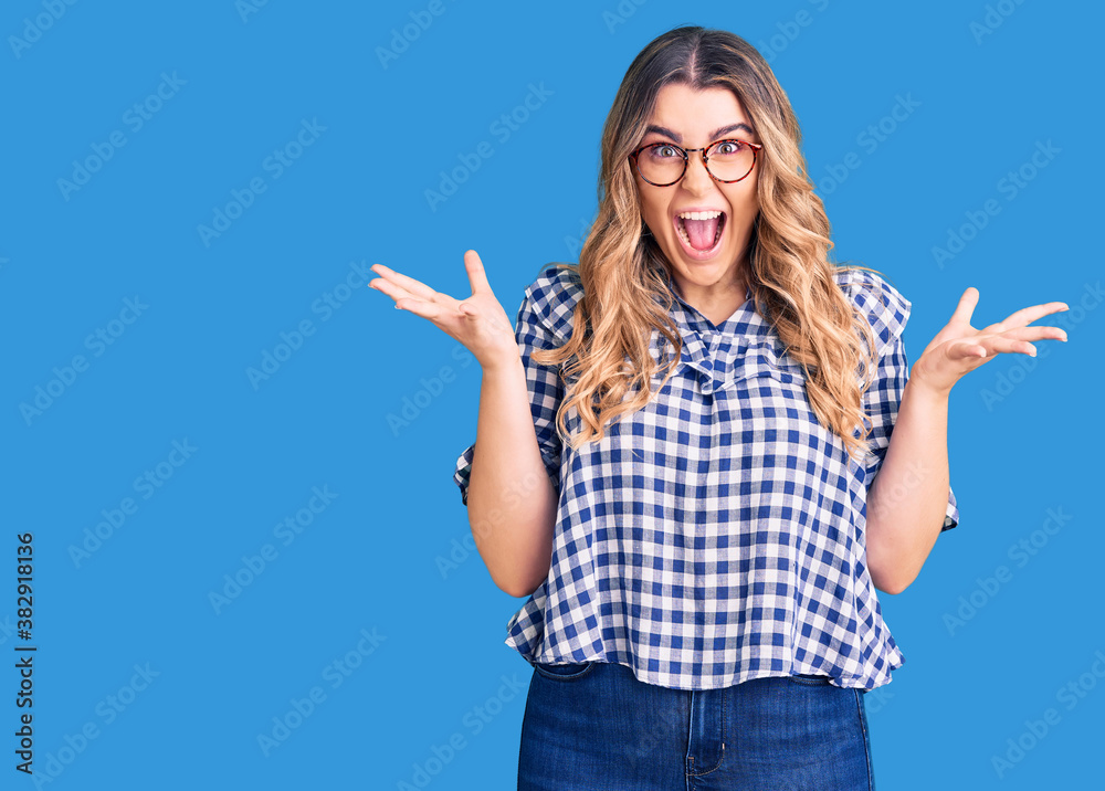 Fototapeta premium Young caucasian woman wearing casual clothes celebrating crazy and amazed for success with arms raised and open eyes screaming excited. winner concept